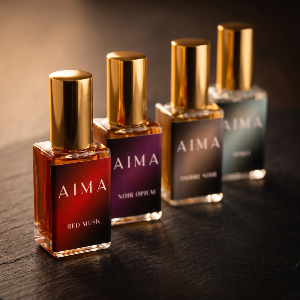 Four AIMA perfume bottles in a diagonal line on a dark surface