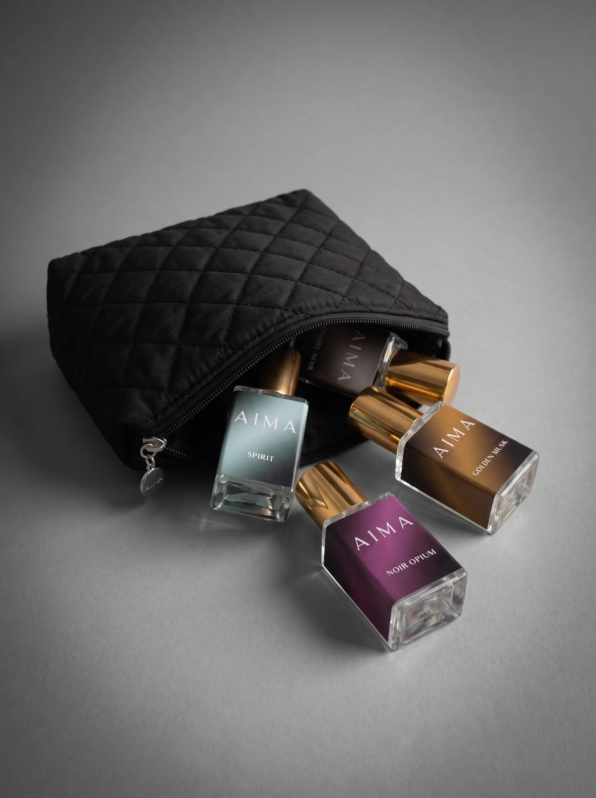 AIMA perfume bottles spilling from a black quilted pouch